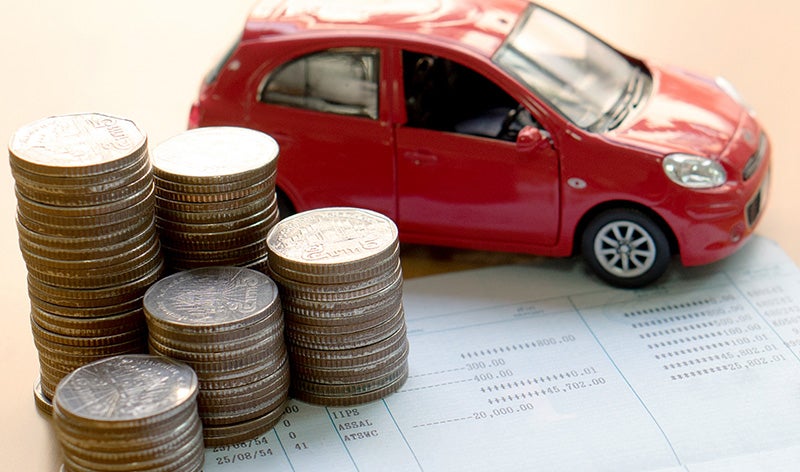 stack of coins and red toy car on paper
